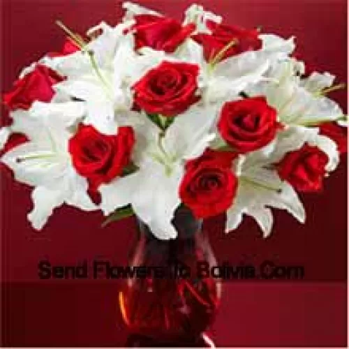 Rose rosse e gigli bianchi con alcune felci in un vaso di vetro